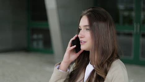 Attractive-girl-outside-talking-on-phone,-looking-serious